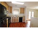 Traditional kitchen with wood cabinets, black appliances, and hardwood floors at 125 Fairhaven Trl, Fairburn, GA 30213
