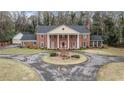 Classic brick home boasts a circular driveway, mature trees, and a timeless, elegant facade at 3074 Cascade Sw Rd, Atlanta, GA 30311