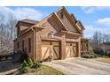 Elegant brick home showing a three-car garage, landscaped yard, and architectural details, blending comfort with sophistication at 117 Olde Heritage Way, Woodstock, GA 30188