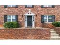 Close-up of the red brick building with a decorative entrance, black door, black iron railings, and trimmed shrubbery at 3665 Chestnut Dr # A2, Atlanta, GA 30340