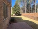 A serene backyard features a brick-paved patio, lush lawn, mature trees, and a brick retaining wall at 7920 Georgetown Cir, Suwanee, GA 30024
