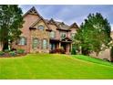 Beautiful two story brick home with stone accents, dormers, manicured landscaping, and a lush green lawn at 6040 Boulder Bluff Dr, Cumming, GA 30040