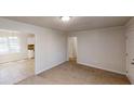 Open-concept living room with adjacent kitchen, featuring carpeted floors and ample natural light at 3359 Mansfield Ln, Snellville, GA 30039