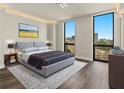 Modern bedroom features hardwood floors, a gray tufted headboard and large windows with city views at 2870 Pharr Court South Nw # 1202, Atlanta, GA 30305