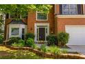 Elegant front door and beautifully landscaped garden bed leading to a two-story brick home at 3242 Monarch Pine Nw Dr, Peachtree Corners, GA 30071