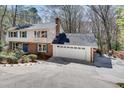 Home exterior with two-car garage, large driveway, brick accents, and an elevated deck at 2242 Greencrest Ne Dr, Atlanta, GA 30345