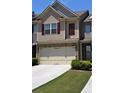 Townhome with neutral siding, red shutters, stone accents, a two-car garage, and green lawn at 3356 Sardis Bend Dr, Buford, GA 30519