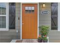 Close-up of a vibrant orange front door with sidelights, stylish hardware, and a welcoming 