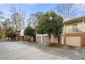 Exterior view showcasing the townhome's garages and the communal parking area with lots of mature trees at 303 Brandywine Cir, Atlanta, GA 30350