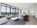 Modern living room featuring sleek furnishings, large windows with a city view, and hardwood floors at 2425 Peachtree Ne Rd # 1705, Atlanta, GA 30305