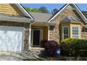 Close-up of a charming home featuring stone and shingle accents, well-manicured landscaping, and an attached two-car garage at 5250 Fieldgate Ridge Dr, Cumming, GA 30028