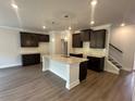 Stylish kitchen featuring dark cabinetry, granite countertops, a central island and wood flooring throughout at 255 Depot Landing Rd # 38, Auburn, GA 30011