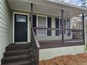 Welcoming front porch featuring a black front door with decorative window, brown steps and green siding at 2179 Summertown Dr, Norcross, GA 30071