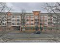 A multi-story building featuring balconies, visible through bare trees on a cloudy day, with street in front at 230 E Ponce De Leon Ave # 327, Decatur, GA 30030