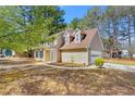 Tan two-story home featuring a well-maintained lawn and two dormer windows at 7438 Chilton Ln, Riverdale, GA 30296