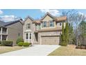 Beautiful two-story home featuring a brick facade, two-car garage, and lush green lawn at 1595 Johnstown Trace, Suwanee, GA 30024