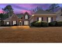 Charming brick home with a well-manicured lawn and mature landscaping at twilight at 2021 Cockrell Pointe Nw, Kennesaw, GA 30152