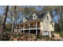 Side view of a two-story home with a stone foundation, a front porch, and lots of landscaping at 705 Mill Creek Rdg, Woodstock, GA 30188