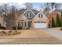 Charming two-story brick home with a well-manicured lawn, attached garage, and a mix of stone and shingle accents at 1525 Camden Cove Dr, Cumming, GA 30040