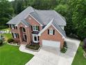 Aerial view of a two-story brick home featuring a spacious driveway and well-kept lawn at 335 Lake Bluff Ct, Suwanee, GA 30024