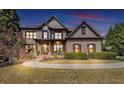Elegant home with a brick facade, covered porch with seating, and a landscaped front yard creates a welcoming entrance at 4020 Toulon Ln, Cumming, GA 30040