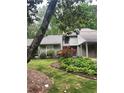 Well-maintained home exterior with mature trees, flowering shrubs, and lush lawn creating a serene setting at 165 Woodhaven Way, Alpharetta, GA 30009