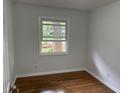 Bright bedroom featuring hardwood floors, a window with natural light, and fresh neutral walls at 877 Verona Dr, Clarkston, GA 30021