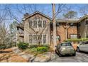 View of tan and brick condominium featuring a balcony and parked car near green bushes at 102 Barrington Hills Dr, Atlanta, GA 30350