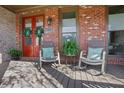 Cozy front porch with rocking chairs, vibrant red door, and charming brick accents at 3123 Neal Ct, Cumming, GA 30041