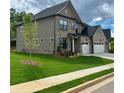 Two-story home with a lush lawn, mature tree, and driveway leading to a two car garage at 4190 Hosch Reserve Dr, Buford, GA 30519