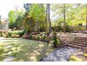 Beautifully landscaped backyard with stone paver pathway, grass, and garden with flowers and greenery at 825 Glengate Pl, Atlanta, GA 30328