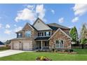 Beautiful two-story home with stone accents, three-car garage, a well-kept lawn, and colorful flower beds at 1301 Odell Ct, Hoschton, GA 30548