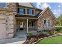Charming front porch with stone columns, lush landscaping, and a welcoming entrance to this lovely home at 1301 Odell Ct, Hoschton, GA 30548
