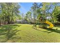 Large backyard with a play structure, a green lawn, and a wooded fence line at 10070 Timberstone Rd, Johns Creek, GA 30022