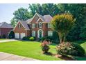 Lovely brick home featuring lush green lawn, mature trees, and colorful rose bushes at 1192 Lake Washington Dr, Lawrenceville, GA 30043