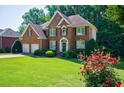 Beautiful brick home with green lawn, manicured shrubs, and vibrant rose bushes at 1192 Lake Washington Dr, Lawrenceville, GA 30043