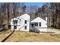 A shot of the white siding, modern house exterior with black trim, set amidst a natural wooded backdrop at 5017 Tanaga Ct, Stone Mountain, GA 30087