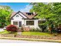 Charming two-story home with white painted brick, dark trim, landscaped yard, and stone accent wall at 1448 N Highland Ne Ave, Atlanta, GA 30306