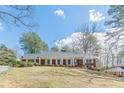Brick house with white columns and shutters on a green lawn under a sunny sky at 3390 Somerset Sw Trl, Atlanta, GA 30331