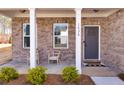 Inviting front porch with brick facade, cozy seating, and a welcoming entrance door at 1436 Maston Rd, Auburn, GA 30011