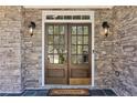 Elegant double front doors with glass panes, flanked by sconces and set in a stone facade at 6230 Hampton Highlands Dr, Cumming, GA 30041