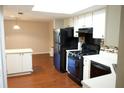 A bright kitchen is featured with a skylight, white cabinetry and black appliances and wood floor at 2211 Surrey Se Ct, Marietta, GA 30067