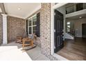 Inviting front porch featuring rocking chairs, brick accents, and a view into the foyer at 3878 Amicus Dr, Buford, GA 30519