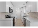 Bright galley kitchen featuring modern stainless steel appliances, white cabinetry and stone countertops at 5225 Maple Valley Sw Rd, Mableton, GA 30126