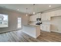Eat in kitchen features a center island with granite counters, white cabinets, and stainless appliances at 704 Bristol Dr, Loganville, GA 30052