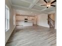 Spacious living room with gray wood flooring, modern ceiling fan, coffered ceilings, and open access to the kitchen at 704 Bristol Dr, Loganville, GA 30052