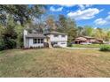 View of the split-level home surrounded by mature trees and a lush green lawn at 3632 Glen Mora Drive, Decatur, GA 30032
