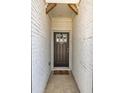 Stylish front door with a window, brick facade, and a decorative 