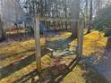 Rustic backyard swing set surrounded by lush greenery and dappled sunlight at 1924 Sidneys Cv, Lawrenceville, GA 30043