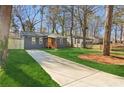 A charming home, nestled amongst trees, featuring a long driveway and a freshly manicured front lawn at 4179 Hanes Dr, Decatur, GA 30035